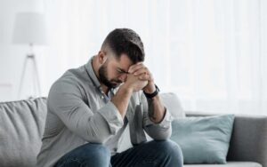 Man sitting with head in hands, symbolizing male depression and silent struggle – therapy and counseling support with Azizeh Rezaiyan LMFT